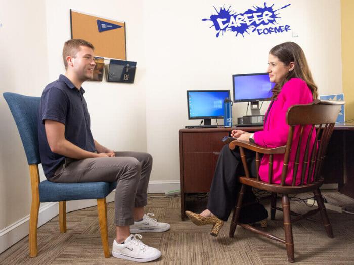 Career Services team member speaks to student. "Career Corner" decal is on wall behind her computer.