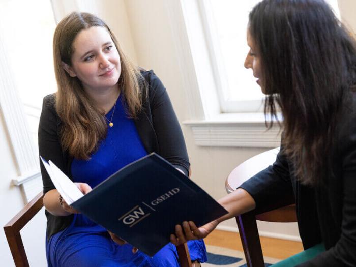 GSEHD staff member presents information in a branded folder to prospective student