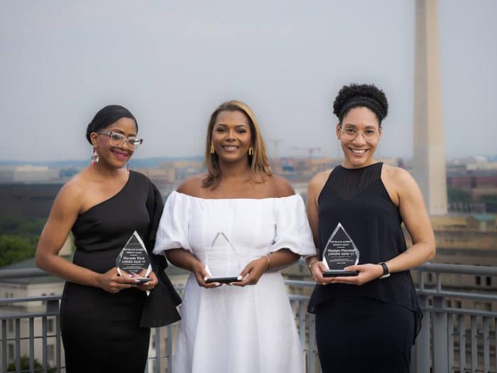 (Left to right) Maranda Ward, Jessica Jackson, and Monique Thornton pose for photos holding awards, Washington Monument in the background (photo courtesy Abby Greenawait/GW Today)