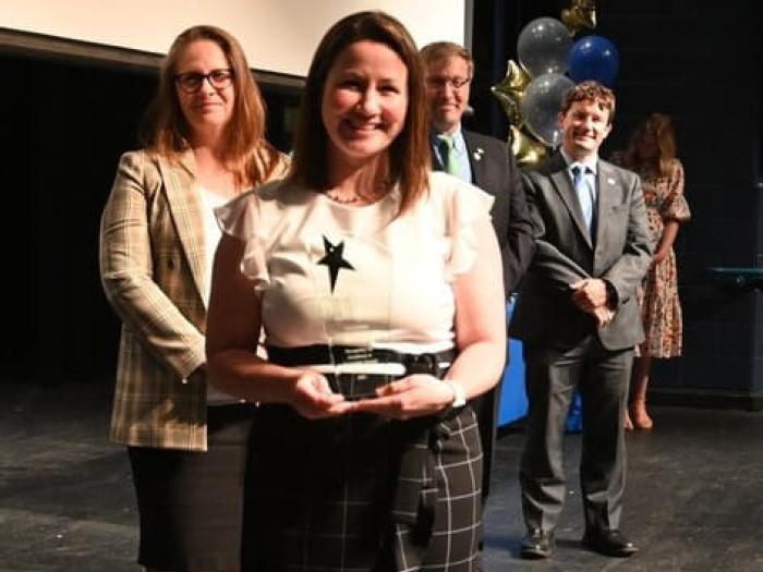 Denise Sokoup poses for photo after receiving the Outstanding Inclusive Administrator Award; presenters in the background