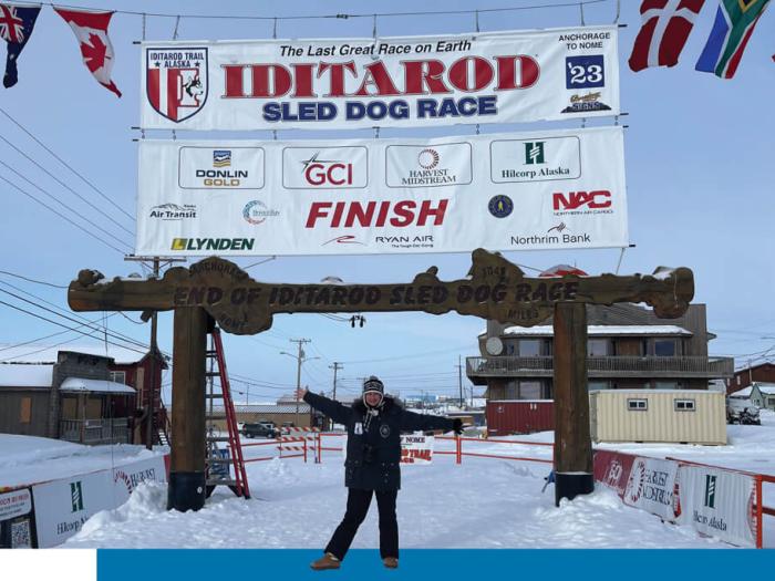 Juli Westrich poses under Iditarod banner