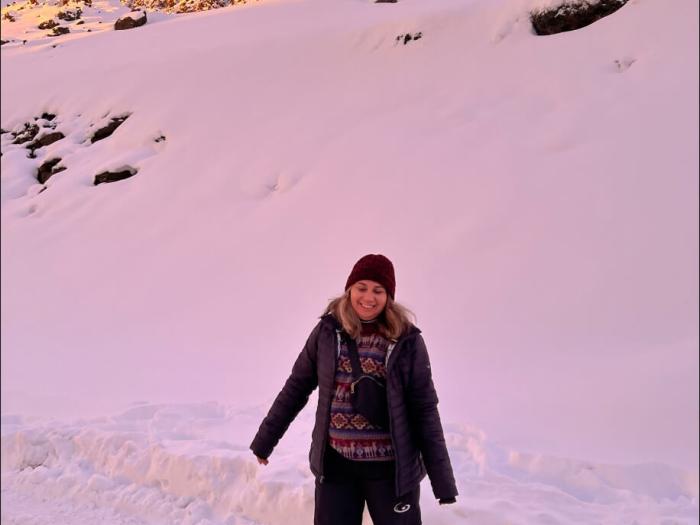 Stacey poses in front of the snowy landscape along the side of the road; pink overlay as the sun sets