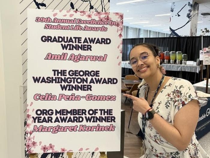 Celia poses with a sign announcing the winners of the excellence awards