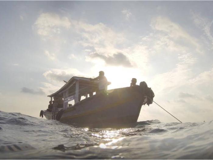 a small boat anchors at sea near the Lesser Sunda Islands
