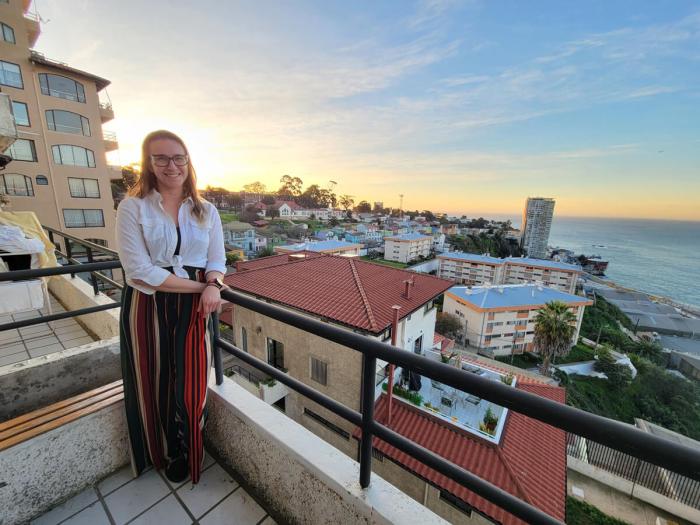 Caroline poses for photo on a balcony in Valparaíso with the town and ocean in the background