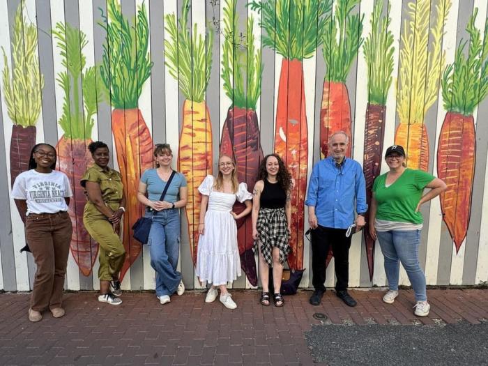 Dr. Eakle and Students pose for group photo in front of carrot mural at the DC Alley Museum