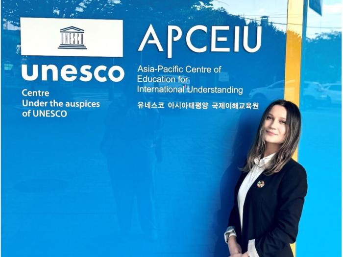 Tishkus poses in front of UNESCO APCEIU main entrance sign