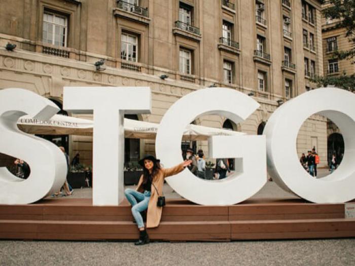 Renny poses for a photo in front of giant letters "STGO" at Plaza de Armas in Santiago’s Historic Center