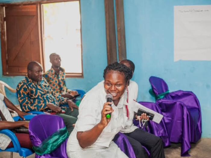 IIES speaker enthusiastically speaks into the microphone, attendees in the background
