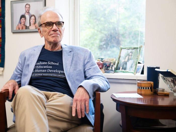 Dean Feuer sits in office chair; Photo Credit: Arwen Clemans, Senior Photo Editor, The Hatchet