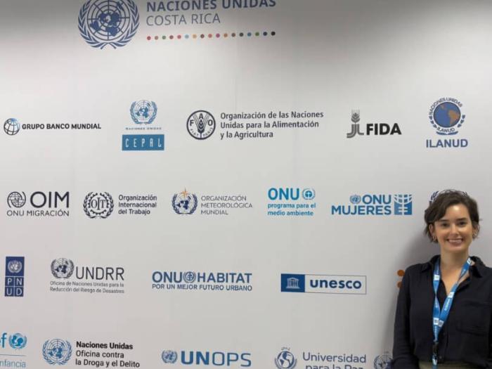 Lily poses for a photo in front of a step-and-repeat banner with various logos At the UNESCO office in San Jose Costa Rica