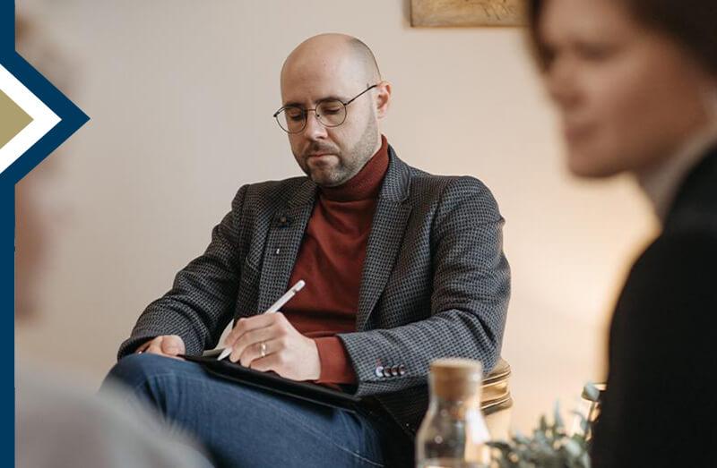 counselor takes notes during session with two patients