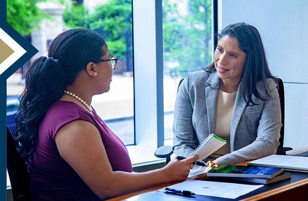 Dr. Natalie Milman speaks to student seated at table