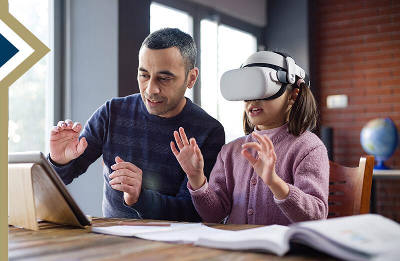 male assists elementary student wearing a VR headset in classroom