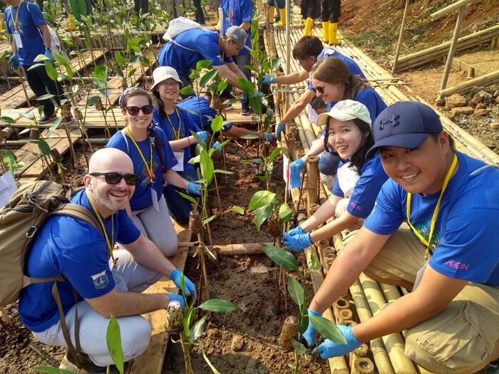 Yoo with group of volunteers planting mangroves