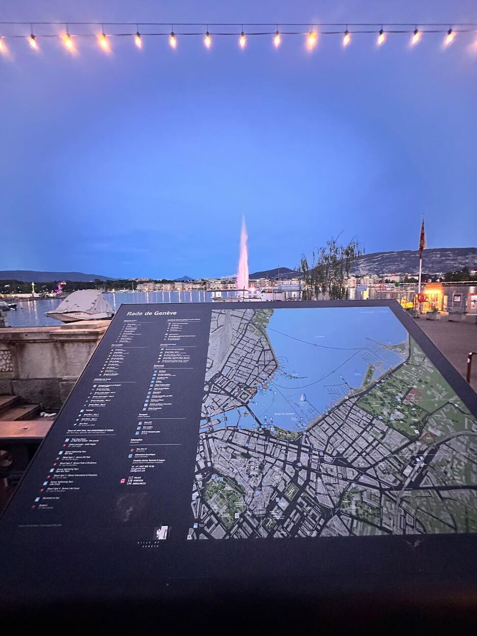 Night shot of the iconic Jet d'Eau fountain in Lake Geneva, with the city skyline in the background.