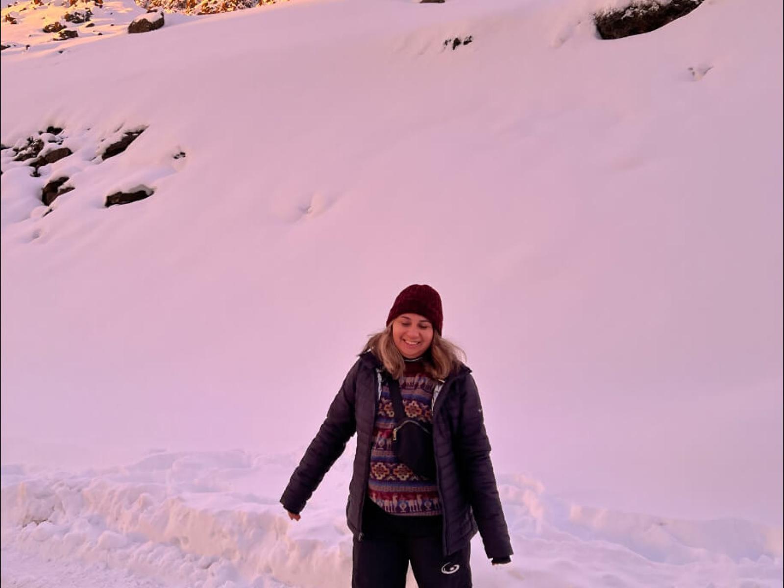Stacey poses in front of the snowy landscape along the side of the road; pink overlay as the sun sets