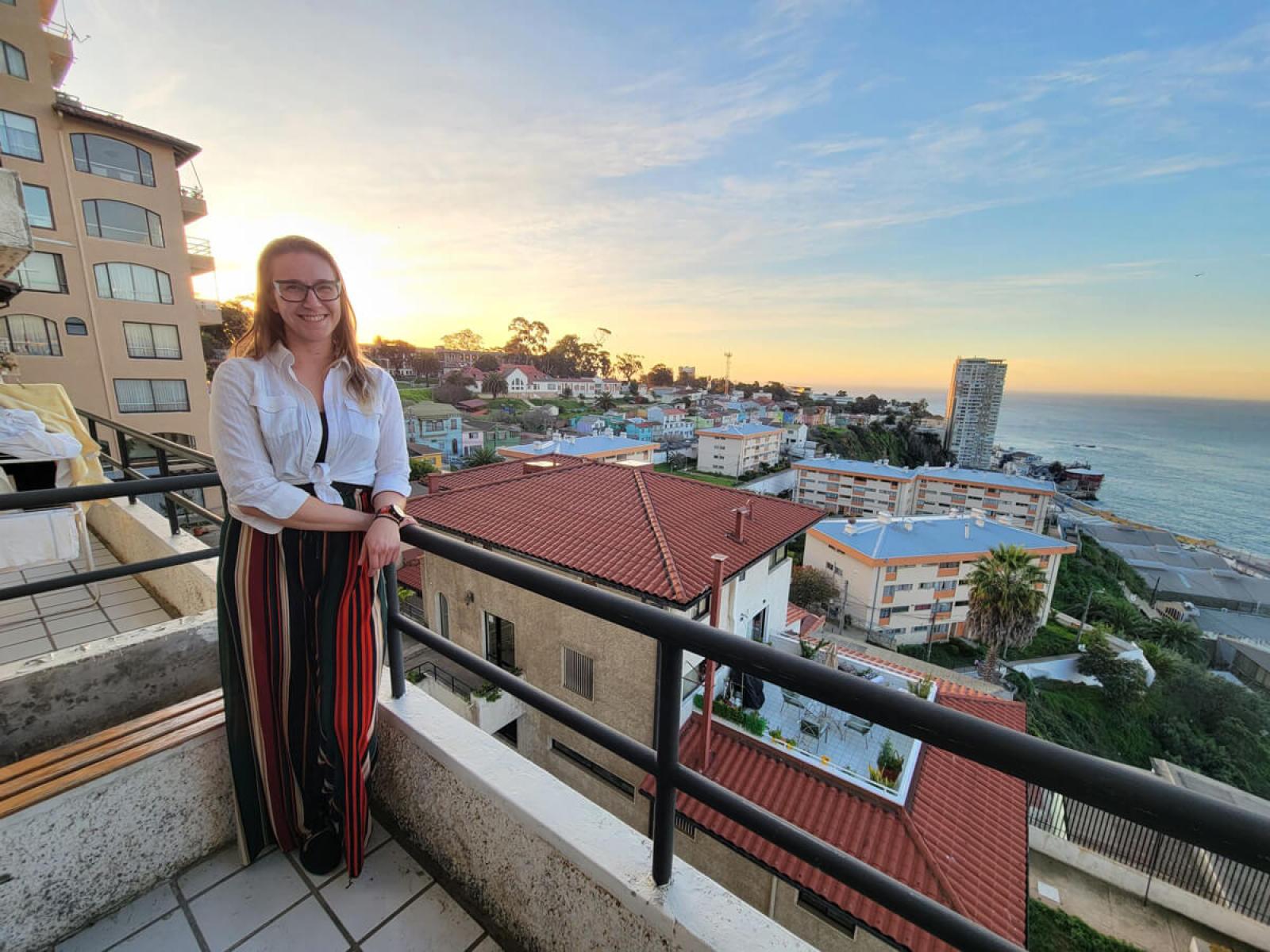 Caroline poses for photo on a balcony in Valparaíso with the town and ocean in the background