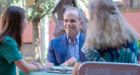 Dr. Feuer speaks to two GSEHD students at outdoor table