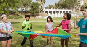 elementary age children playing with colored tarp outside