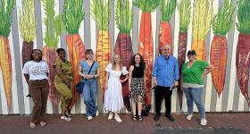 Dr. Eakle and Students pose for group photo in front of carrot mural at the DC Alley Museum