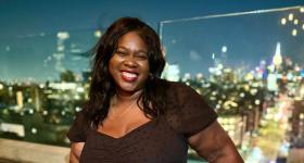 Micha Aime poses for photo with city skyline in the distance
