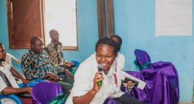 IIES speaker enthusiastically speaks into the microphone, attendees in the background