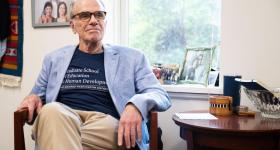Dean Feuer sits in office chair; Photo Credit: Arwen Clemans, Senior Photo Editor, The Hatchet